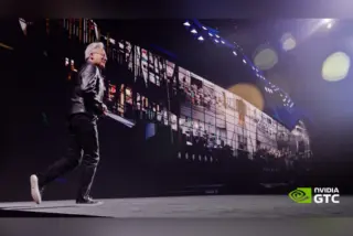 ג'נסן הואנג, מייסד ומנכ"ל NVIDIA, צועד על במה כהה בכנס GTC בברלין, עם מסך ענק מאחוריו