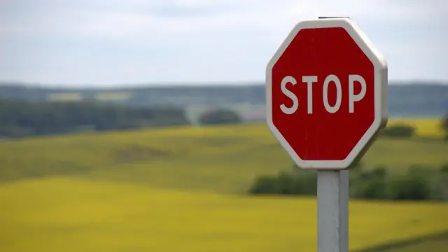 תמרור "STOP" אדום על רקע שדה צהוב ופתוח, כסמל לעצירה ולסירוב
